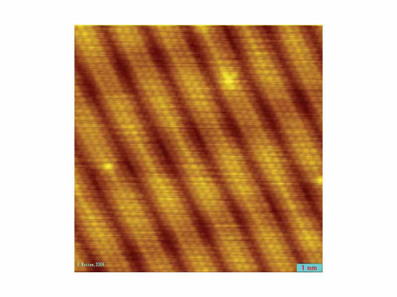 Image of surface reconstruction on a clean Gold (Au(100)) surface, as visualized using scanning tunneling microscopy. The individual atoms composing the material are visible. Surface reconstruction causes the surface atoms to deviate from the bulk crystal structure, and arrange in columns several atoms wide with regularly-spaced pits between them.